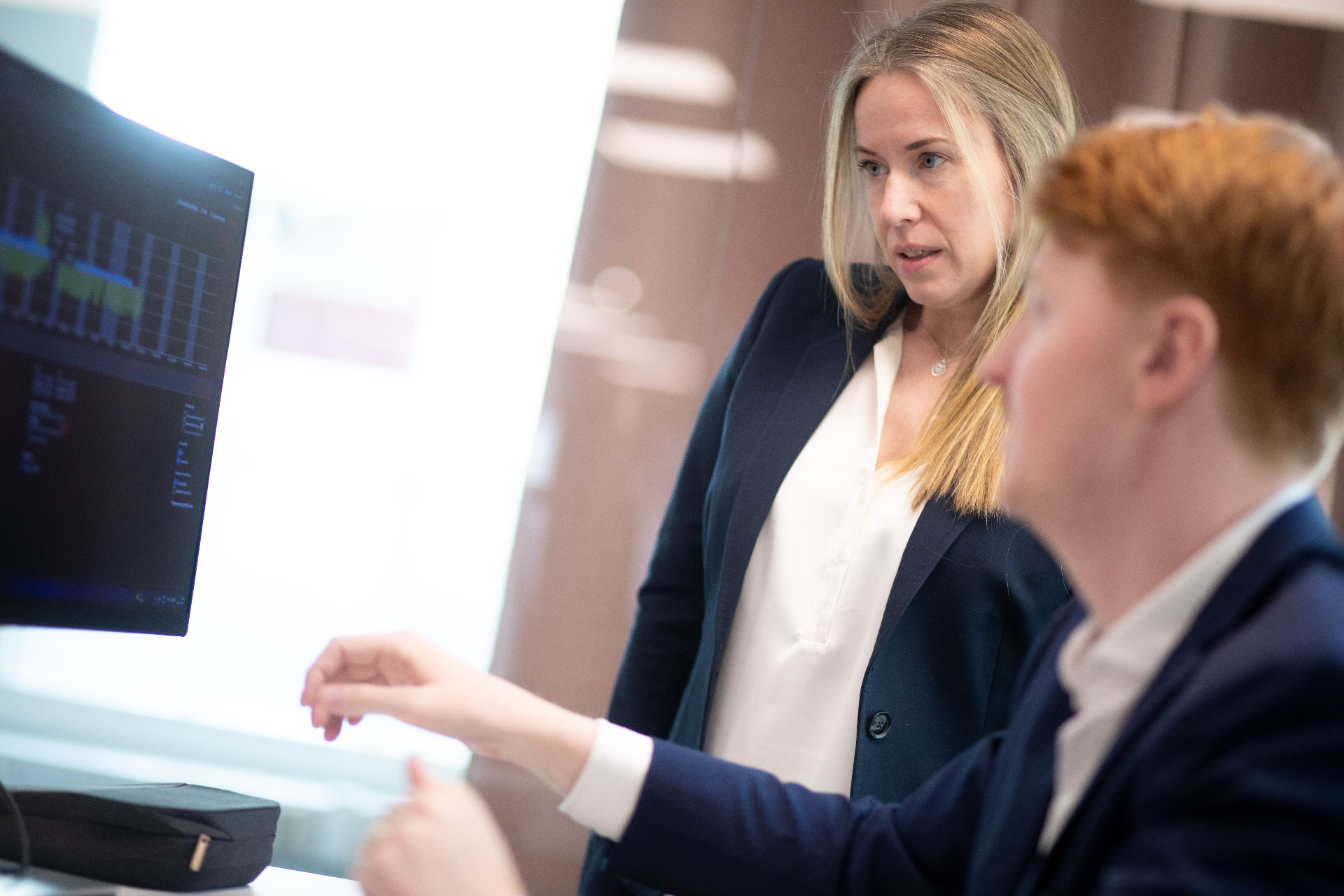 Colleagues collaborating around a table with large operational screens in the background
